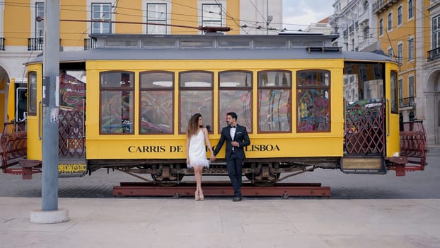Lisbon-Portugal, 04.12.2022: Action. A young European tourist couple poses next to a statue of a bus. Use only for editorial. High quality 4k footage