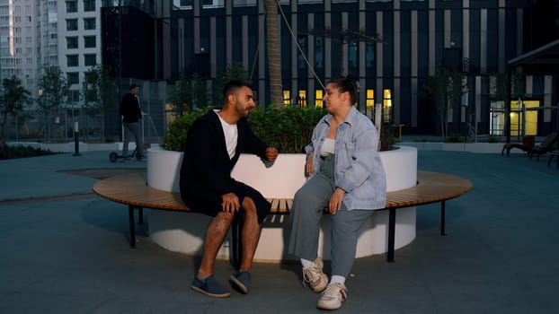 Meeting friends on the street. Media. A beautiful couple of men and women in fashionable clothes who are talking on a bench next to a flat. High quality 4k footage