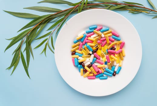 Many colorful pills, nutritional supplements in a white plate on a blue background. Prescription medicine