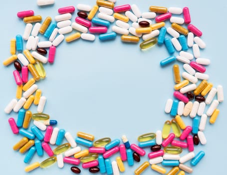 The image shows an assortment of colorful tablets and capsules arranged in a rectangle shape on a blue background. Tablets and capsules of different sizes and colors