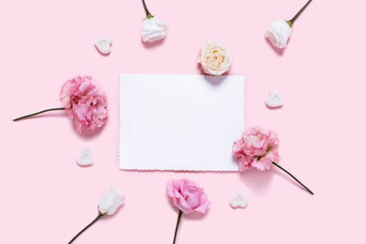 Holiday card. Pink background with sheet of white paper in a center surrounded by roses.