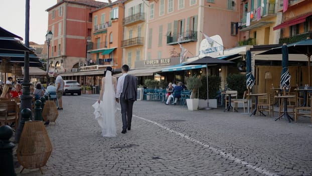 Venice - italy, September 25, 2022: Bride and groom walking in a city street in summer day. Action. Summer street with restaurants and people