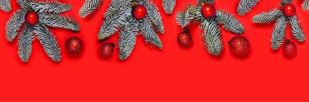 Christmas and New year red web banner with balls on Christmas tree branches. Flat lay, top view, copy space.