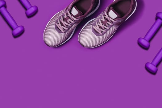 Purple background with sneakers and dumbbels. Flat lay picture.