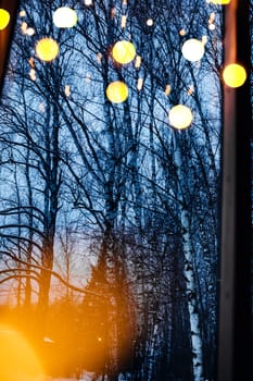 Window overlooking the winter forest in Christmas lights.