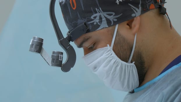 Surgeon head with professional glasses at operating room. Action. Close up side view of a doctor in glasses with binocular magnifiers