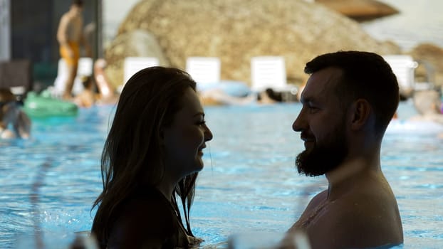 Happy couple embracing in outdoors swimming pool. Clip. Man and woman on a vacation