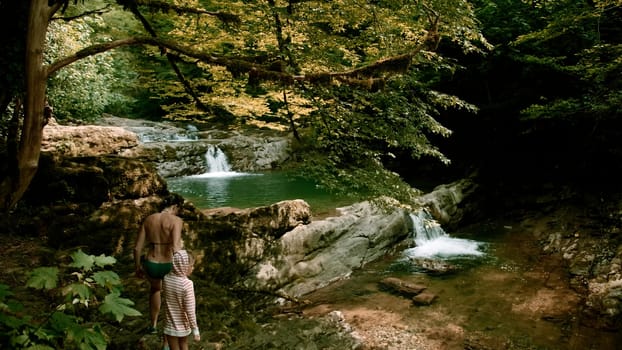 Vacationers and bathing families. Creative.People in swimsuits walking on the lake in the mountains and green thickets of trees are visible. High quality 4k footage