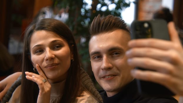 Beautiful couple takes selfie on date. Stock footage. Attractive couple takes selfie on date in cafe. Beautiful young couple takes selfie in cafe.