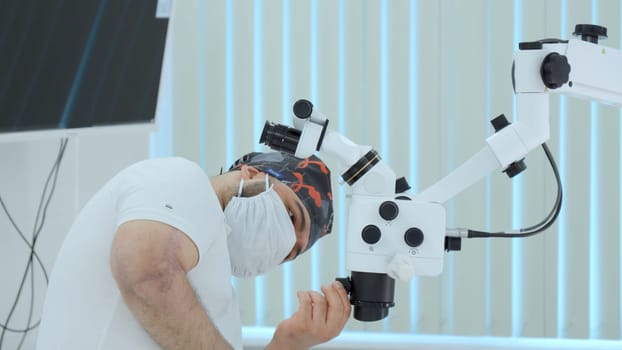 Ophthalmological surgery specialist in front of microscope before operation. Action. Side view of male doctor with medical equipment
