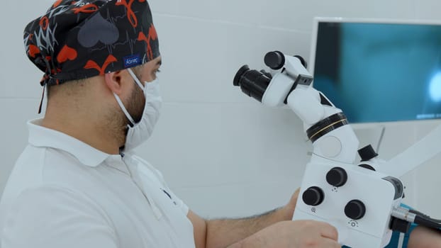 Male doctor using microscope in laboratory. Action. Man in lab examines sample during work in clinic in daytime