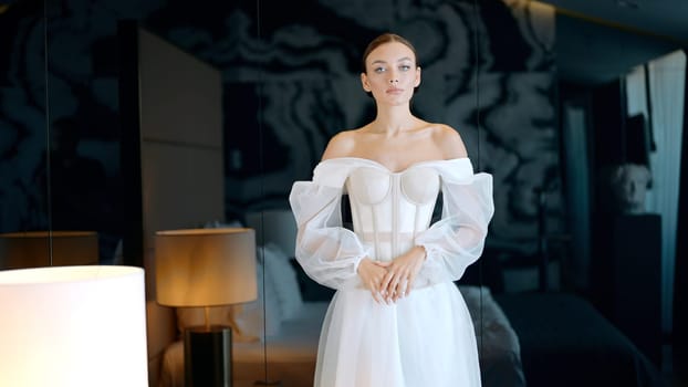 Morning of a bride. Action. Beautiful bride in a hotel room in a wedding dress standing in a beautiful room interior