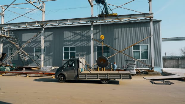 Technician worker using hoist crane for lifting metal detail in workshop factory. Creative. Work process and machinery