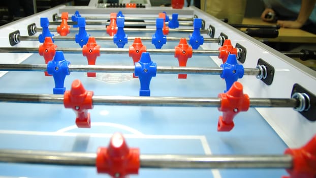Table football soccer game kicker . Table football game, Soccer table with red and blue players. Young friends playing table football together indoors.
