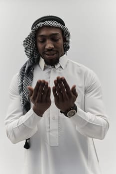 African American Muslim man raises his hands in prayer, seeking solace and devotion to God, as he stands isolated against a serene white backdrop, symbolizing a profound expression of faith and contemplation.