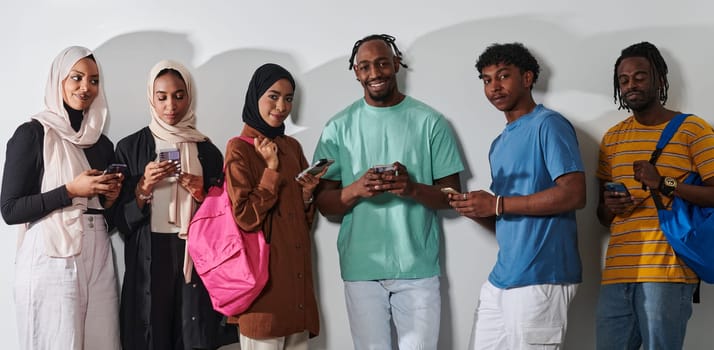 A diverse group of students, immersed in the digital age, stands united while engaging with their smartphones against a white backdrop, symbolizing the modern era of connectivity, communication, and collaborative learning.