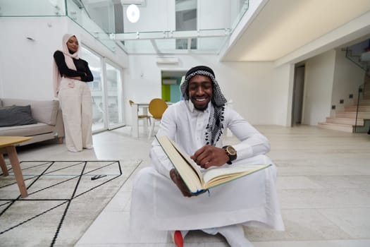 In the sacred month of Ramadan, an African American Muslim man engrossed in reading the Holy Quran is surrounded by a backdrop where three hijab-wearing women prepare and serve food for iftar, portraying a scene of spiritual devotion, cultural unity, and communal celebration.