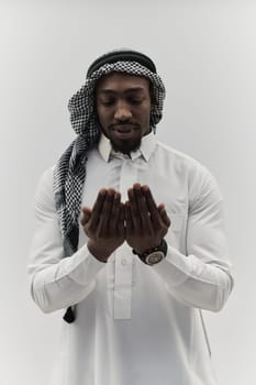 African American Muslim man raises his hands in prayer, seeking solace and devotion to God, as he stands isolated against a serene white backdrop, symbolizing a profound expression of faith and contemplation.