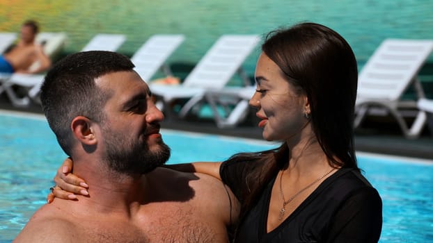 Portrait of loving couple having fun on summer vacation in outdoor swimming pool. Clip. Concept of relax and travelling