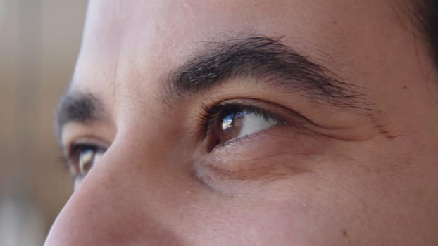 Close-up of brown eyes of man looking into distance. Action. Man with bright brown eyes looks with admiration. Joyful and admiring look of man.