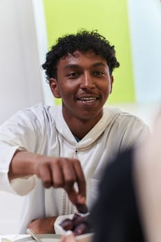 African American Muslim man delicately takes dates to break his fast during the Ramadan month, seated at the family dinner table, embodying a scene of spiritual reflection, cultural tradition, and the shared anticipation of the communal iftar.