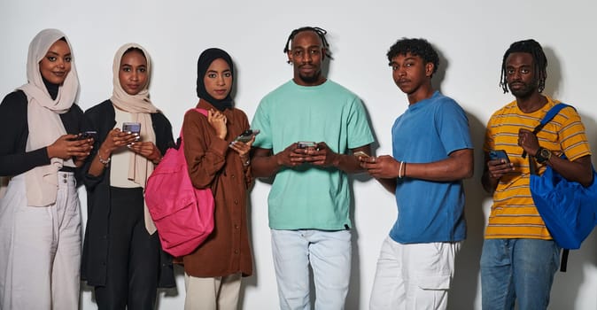 A diverse group of students, immersed in the digital age, stands united while engaging with their smartphones against a white backdrop, symbolizing the modern era of connectivity, communication, and collaborative learning.