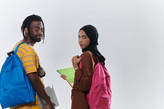 African American student collaborates with his Muslim colleague, who diligently works on her laptop, symbolizing a blend of diversity, modern learning, and cooperative spirit against a serene white background.