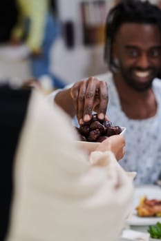 African American Muslim man delicately takes dates to break his fast during the Ramadan month, seated at the family dinner table, embodying a scene of spiritual reflection, cultural tradition, and the shared anticipation of the communal iftar.