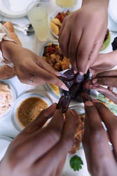 In a poignant close-up, the diverse hands of a Muslim family delicately grasp fresh dates, symbolizing the breaking of the fast during the holy month of Ramadan, capturing a moment of cultural unity, shared tradition, and the joyous anticipation of communal iftar.