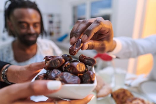 In a poignant close-up, the diverse hands of a Muslim family delicately grasp fresh dates, symbolizing the breaking of the fast during the holy month of Ramadan, capturing a moment of cultural unity, shared tradition, and the joyous anticipation of communal iftar.