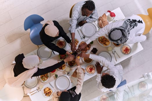 Top view of diverse hands of a Muslim family delicately grasp fresh dates, symbolizing the breaking of the fast during the holy month of Ramadan, capturing a moment of cultural unity, shared tradition, and the joyous anticipation of communal iftar.