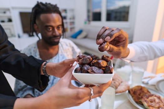 In a poignant close-up, the diverse hands of a Muslim family delicately grasp fresh dates, symbolizing the breaking of the fast during the holy month of Ramadan, capturing a moment of cultural unity, shared tradition, and the joyous anticipation of communal iftar.