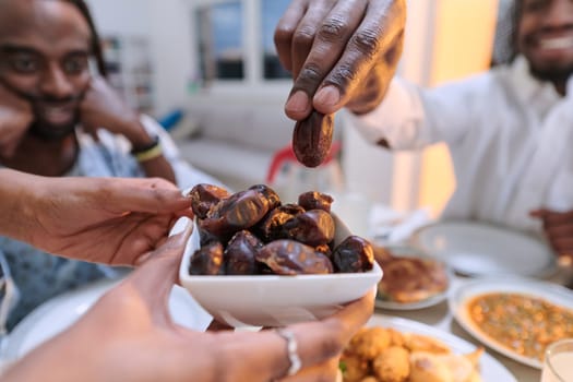 In a poignant close-up, the diverse hands of a Muslim family delicately grasp fresh dates, symbolizing the breaking of the fast during the holy month of Ramadan, capturing a moment of cultural unity, shared tradition, and the joyous anticipation of communal iftar.