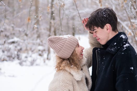 A young couple walks in the park in winter. Guy and girl fooling around on the street