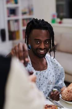 African American Muslim man delicately takes dates to break his fast during the Ramadan month, seated at the family dinner table, embodying a scene of spiritual reflection, cultural tradition, and the shared anticipation of the communal iftar.