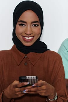 An elegant Arab woman, adorned in a hijab, engages with modernity as she uses a smartphone, the juxtaposition of traditional attire against contemporary technology captured in the isolated setting against a pristine white background.