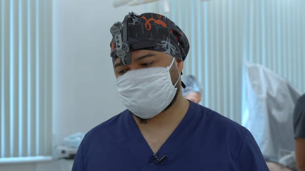 Neurosurgeon and anesthesiologist behind him before the procedure. Action. Concept of healthcare