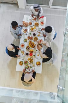 Top view of traditional and diverse Muslim family comes together to share a delicious iftar meal during the sacred month of Ramadan, embodying the essence of familial joy, cultural richness, and spiritual unity in their shared celebration.