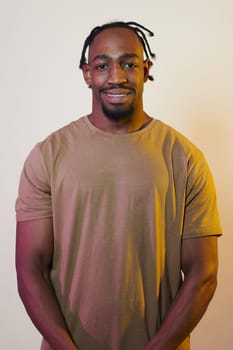 A charismatic and stylish African American man commands attention against a vibrant yellow gel background, showcasing his confident and contemporary fashion sense, radiating charm and sophistication in a striking portrait.