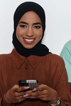 An elegant Arab woman, adorned in a hijab, engages with modernity as she uses a smartphone, the juxtaposition of traditional attire against contemporary technology captured in the isolated setting against a pristine white background.