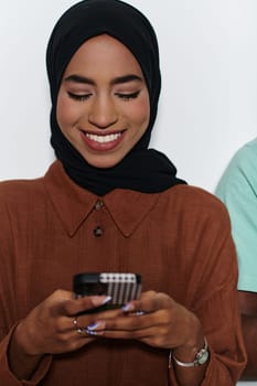 An elegant Arab woman, adorned in a hijab, engages with modernity as she uses a smartphone, the juxtaposition of traditional attire against contemporary technology captured in the isolated setting against a pristine white background.