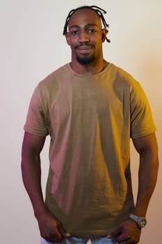 A charismatic and stylish African American man commands attention against a vibrant yellow gel background, showcasing his confident and contemporary fashion sense, radiating charm and sophistication in a striking portrait.