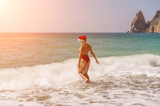 A woman in Santa hat on the seashore, dressed in a red swimsuit. New Year's celebration in a hot country.