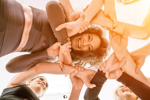 Team of people holding hands. Group of happy young women holding hands. Bottom view, low angle shot of human hands. Friendship and unity concept.