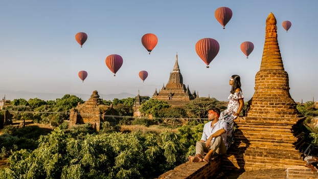 Bagan Myanmar, a couple of men and women looking at the sunrise on top of an old pagoda temple. a couple on vacation in Myanmar Asia visit the historical site of Bagan