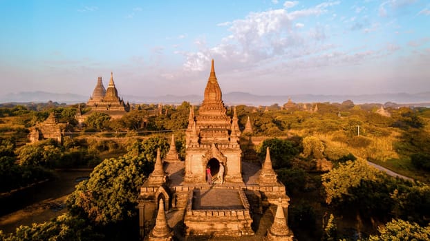 Bagan Myanmar, a couple of men and women are looking at the sunrise on top of an old pagoda temple. a couple on vacation in Myanmar Asia visit the historical site of Bagan Myanmar