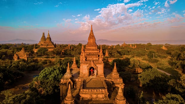 Bagan Myanmar, a couple of men and women are looking at the sunrise on top of an old pagoda temple. a couple on vacation in Myanmar