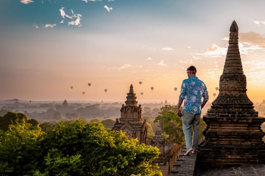 Bagan Myanmar, young men looking at the sunrise on top of an old pagoda temple. a European man on vacation in Myanmar Asia visit the historical site of Bagan