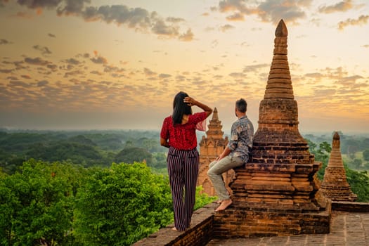 Bagan Myanmar, a couple of men and women looking at the sunrise with a foggy landscape on top of an old pagoda temple. a couple on vacation in Myanmar Asia visit the historical site of Bagan