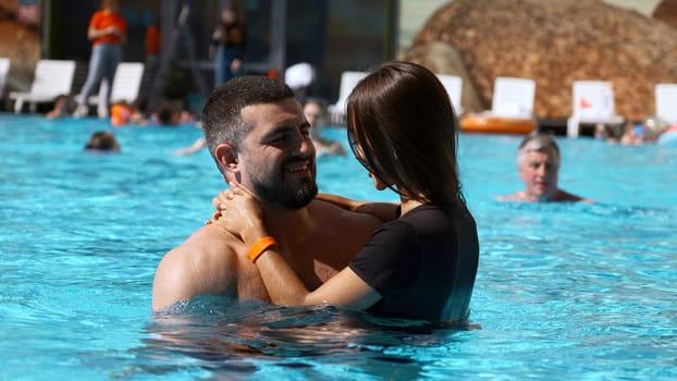 Young woman and man relaxing in resort pool. Clip. Couple enjoying holidays at luxury resort